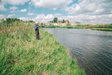 Fisherman on a Grassy Riverbank