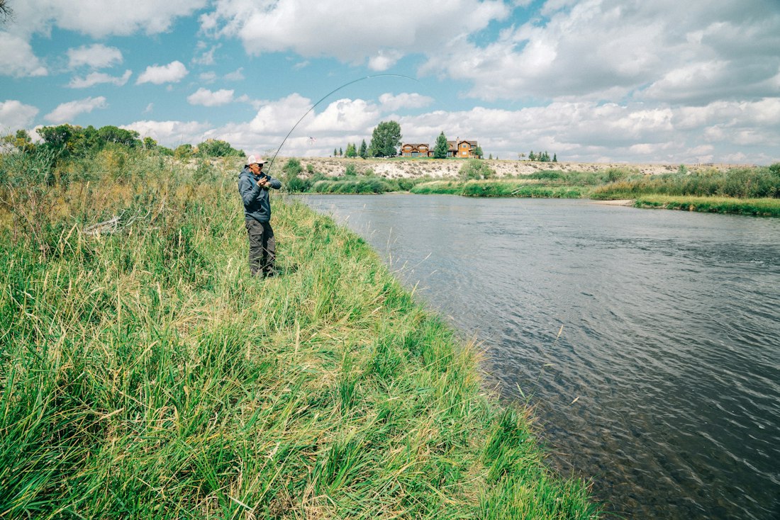 Fisherman on a Grassy Riverbank